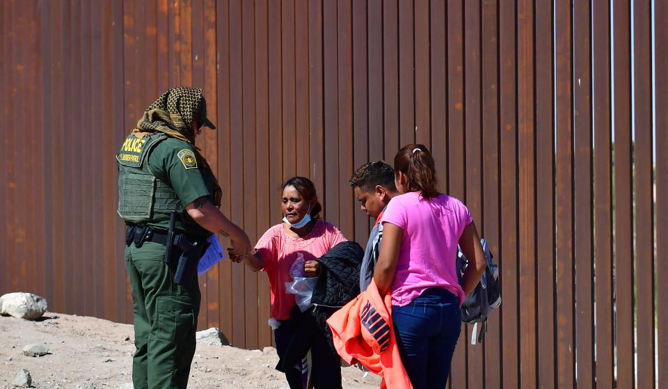 Migrant Gladys Martinez offers paperwork to a US Border Patrol agent upon arrival at the US-Mexico border wall separating Algodones, Mexico, from Yuma, Arizona, on May 16, 2022 / Credit: FREDERIC J. BROWN/AFP via Getty Images