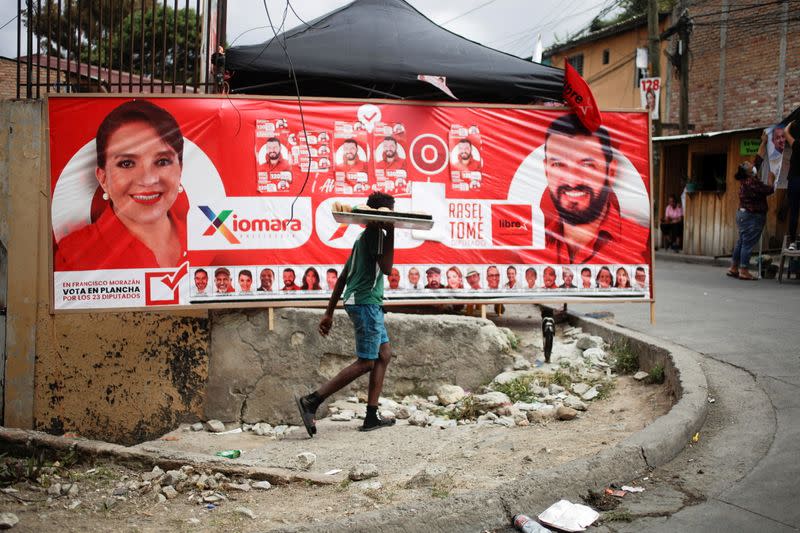 FILE PHOTO: A young man passes in front of a banner of the Libre Party presidential candidate Xiomara Castro ahead of the November 28 general election in Tegucigalpa