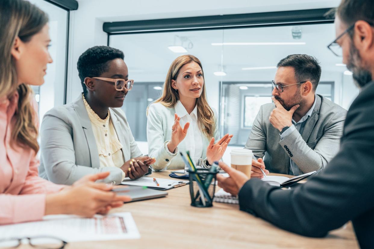 Modern business team discussing new ideas at the office. Business people on meeting in modern office. Colleagues smiling and talking at board room. Brainstorming