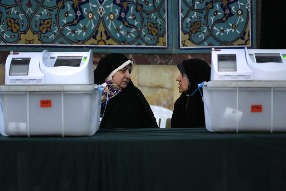 Staff members of a polling station talk during the parliamentary runoff elections in Tehran, Iran, Friday, May 10, 2024. Iranians voted Friday in a runoff election for the remaining seats in the country's parliament after hard-line politicians dominated March balloting. (AP Photo/Vahid Salemi)