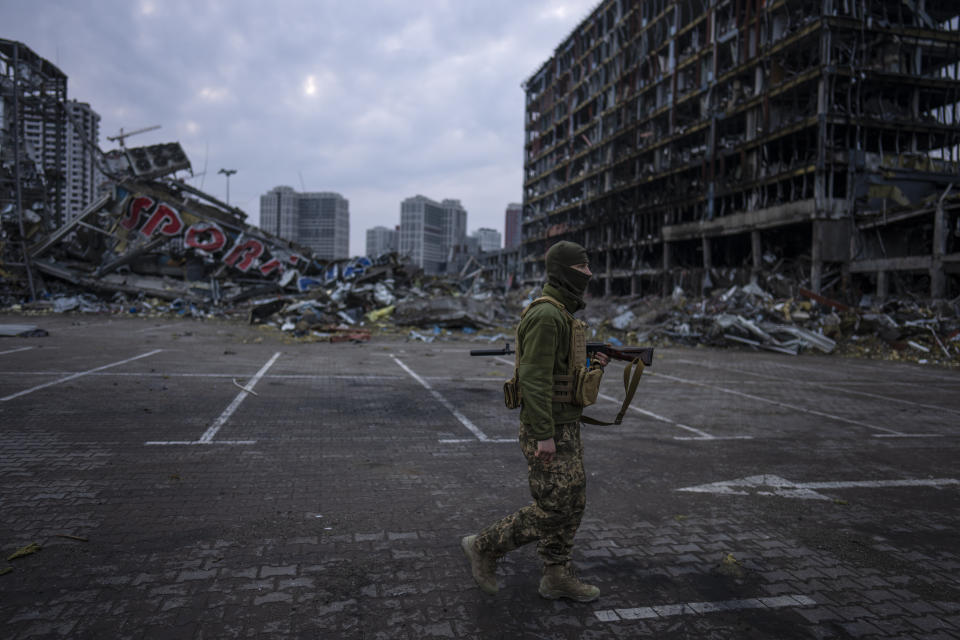 FILE - A soldier walks the amid the destruction caused after shelling of a shopping center last March 21 in Kyiv, Ukraine, March 30, 2022. Disinformation about Russia's invasion of Ukraine is surging in Spanish, as content crafted for a Latin American audience gets a boost from the Kremlin. (AP Photo/Rodrigo Abd, File)