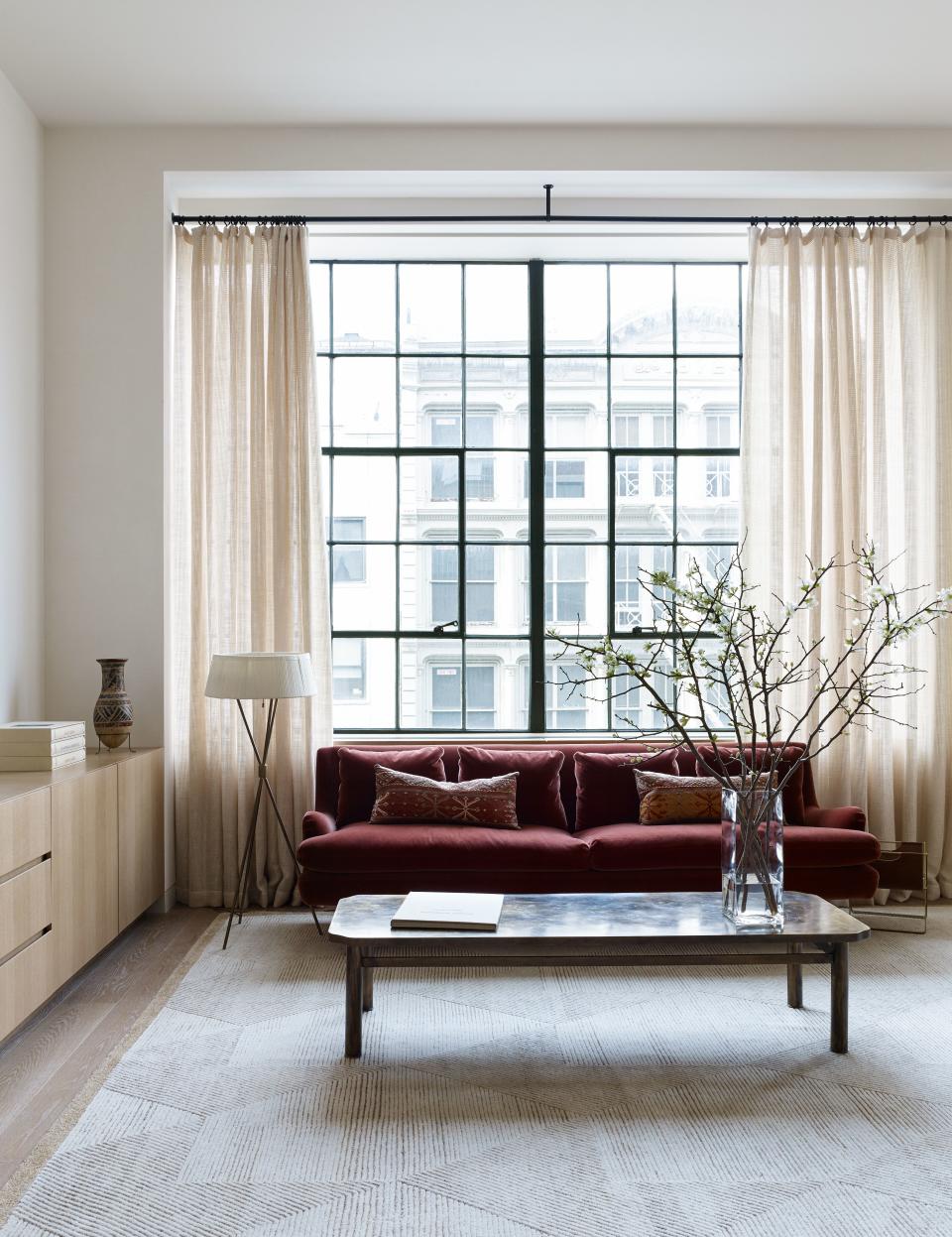 The master sitting area features a deep-rose sofa by Vladimir Kagan purchased from Ralph Pucci in mohair fabric from Rose Tarlow. The coffee table is an American design from 1968 by Philip and Kelvin LaVerne, and purchased at Donzella. The rug is from FJ Hakimian, and the custom drapes were made with fabric by de Le Cuona.