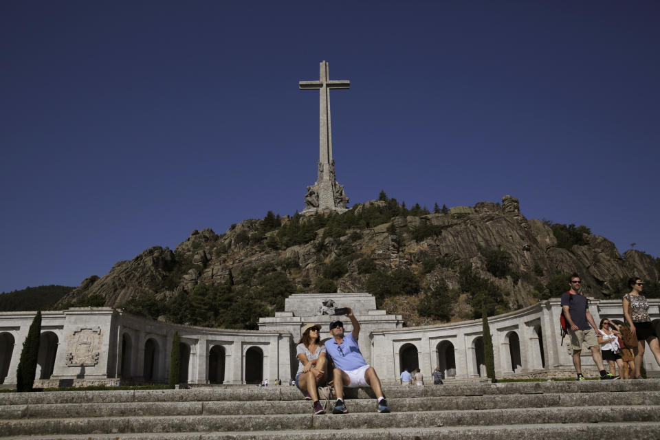 A couple take a photo at the Valley of the Fallen monument at El Escorial, in El Escorial, Spain, Friday, Aug. 24, 2018. Spain's center-left government has approved legal amendments that it says will ensure the remains of former dictator Gen. Francisco Franco can soon be dug up and removed from a controversial mausoleum. (AP Photo/Andrea Comas)