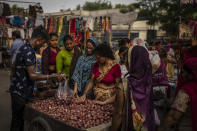 A roadside vendor packs onions in plastic bags as women shop at a weekly market in New Delhi, India, Wednesday, June 29, 2022. India banned some single-use or disposable plastic products Friday as a part of a longer federal plan to phase out the ubiquitous material in the nation of nearly 1.4 billion people. (AP Photo/Altaf Qadri)