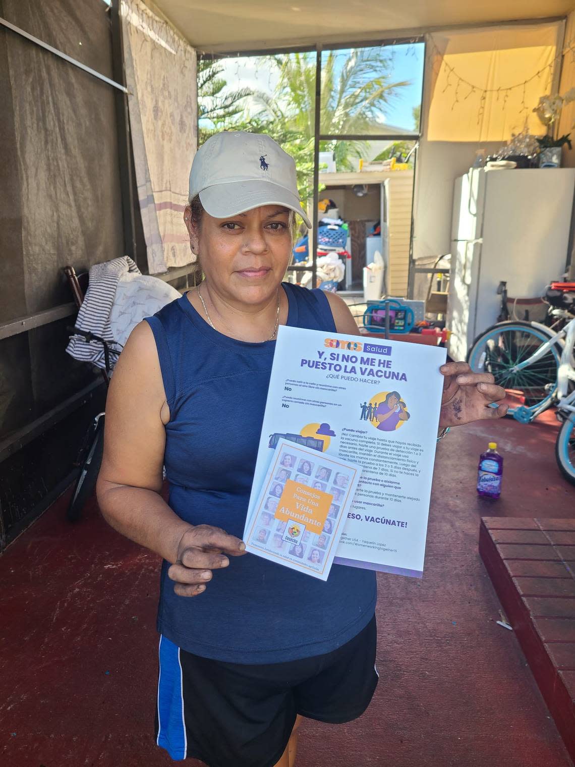 A woman poses with COVID-19 vaccine information provided by Women Working Together through the Cosecha project.