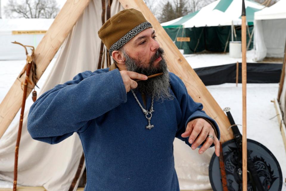 After spending the night in the tent behind him, Allen McDonald, 46, of Davison, and a member of the Michigan Viking Alliance gets ready for another day at the Michigan Nordic Fire Festival at the Eaton County Fairgrounds in Charlotte on Saturday, Feb. 25, 2023.