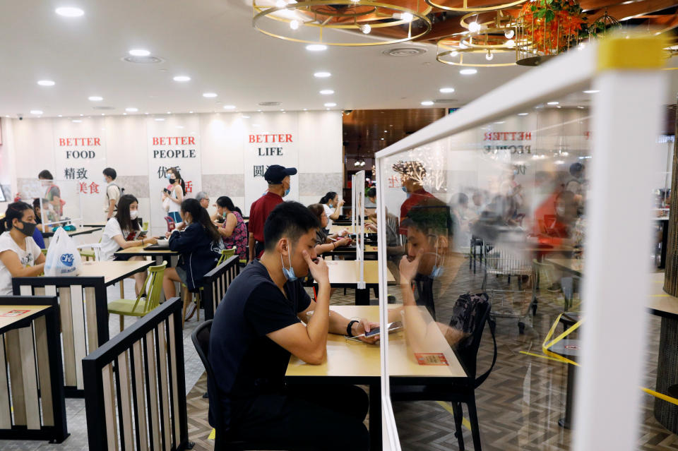 People eat at tables installed with plexiglass dividers at a food court in Singapore as the city state reopens the economy amid the coronavirus disease (COVID-19) outbreak, June 19, 2020.  REUTERS/Edgar Su