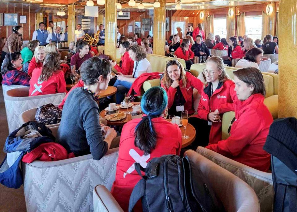 Women in red shirts are sitting around a table.