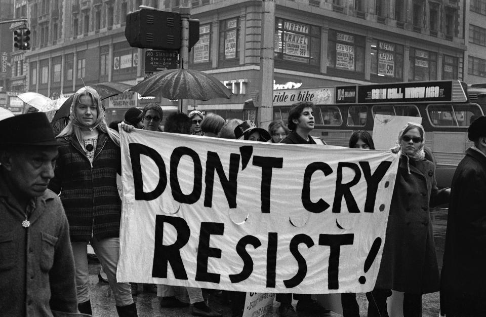 View of activists Anne Koedt and Carol Hanisch as they hold a banner that reads 'Don't Cry, Resist' during a 'Legalize Abortion' demonstration in Times Square (looking southeast across the intersection of Broadway and West 42nd Street), New York, New York, March 1968. The building in the background is the Knickerbocker Hotel.