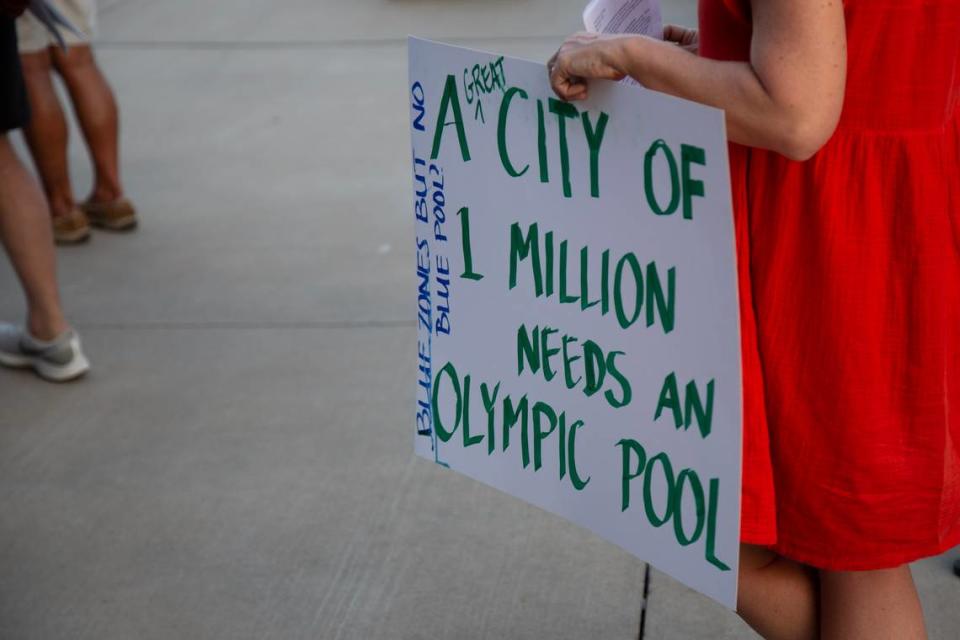 A woman holds up a sign at a community meeting to discuss replacing the Forest Park Pool.