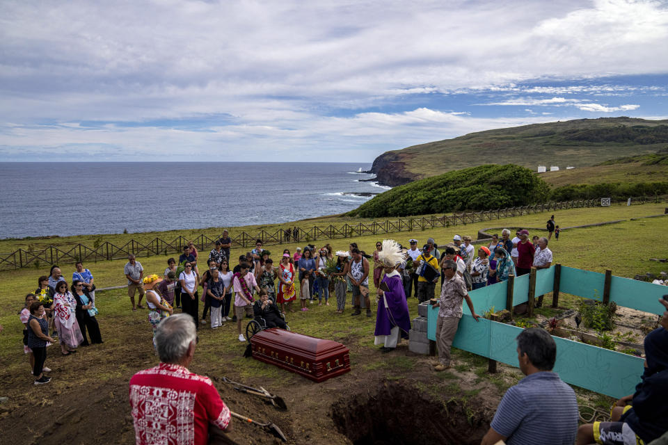 Locals attend the burial ceremony of Emilio Araki, a horse breeder, at the cemetery in Hanga Roa, Rapa Nui, or Easter Island, Chile, Saturday, Nov. 26, 2022. The Catholic priest said that the hat he wears was gifted to him by the local Rapanui community, as a symbol of hierarchy. (AP Photo/Esteban Felix)