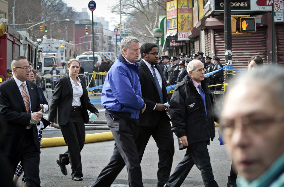 Mayor Bill de Blasio, center, arrives to visit the site of an explosion that leveled two apartment buildings in the East Harlem neighborhood of New York, Wednesday, March 12, 2014. Con Edison spokesman Bob McGee says a resident from a building adjacent to the two that collapsed reported that he smelled gas inside his apartment, but thought the odor could be coming from outside. (AP Photo/Bebeto Matthews)