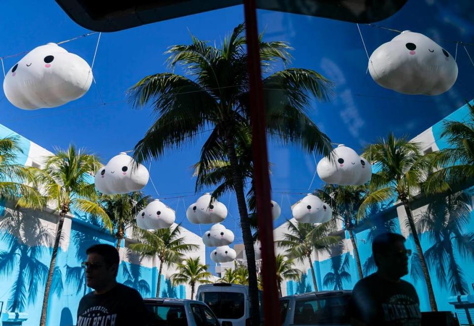 A pedestrian makes his way past Little Cloud Sky by FriendsWithYou near Washington Avenue and Española Way in Miami Beach.