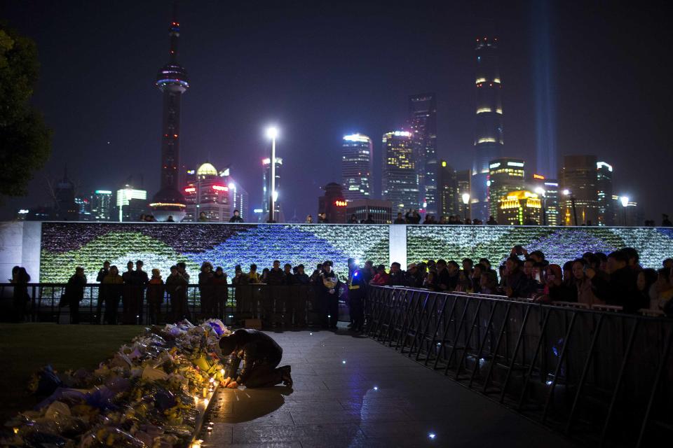 Man lights a candle during a memorial ceremony for people who were killed in a stampede incident during a New Year's celebration on the Bund, in Shanghai