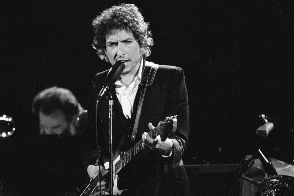 El músico Bob Dylan toca con The Band en el Forum de Los Angeles el 15 de febrero de 1974. El catálogo completo de canciones de Dylan, que abarca 60 años y está entre los más preciados, junto con el de los Beatles, fue adquirido por Universal Music Publishing Group en un acuerdo cuyos términos financieros no fueron revelados. (AP Foto/Jeff Robbins, Archivo)
