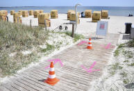 In this Wednesday, May 20, 2020 photo, pylons and arrows sprayed on the ground, regulate the access to the beach at the Baltic Sea in Haffkrug, Germany. Germany's states, which determine their own coronavirus-related restrictions, have begun loosening lockdown rules to allow domestic tourists to return. (Daniel Bockwoldt/dpa via AP)