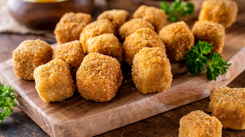 Crumbed fish nuggets on wooden board