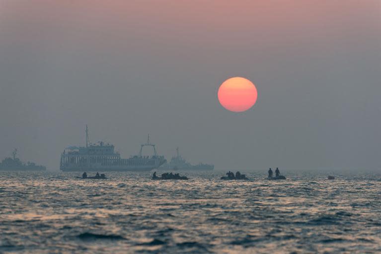 The sun sets behind coast guard boats and search and rescue teams as they take part in recovery operations at the site of the 'Sewol' ferry off the coast of the South Korean island of Jindo on April 22, 2014