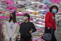 Visitors wearing face masks walk under colorful umbrellas on display along a hutong alley near Qianmen Avenue, a popular tourist spot in Beijing, Thursday, Oct. 14, 2021. (AP Photo/Andy Wong)