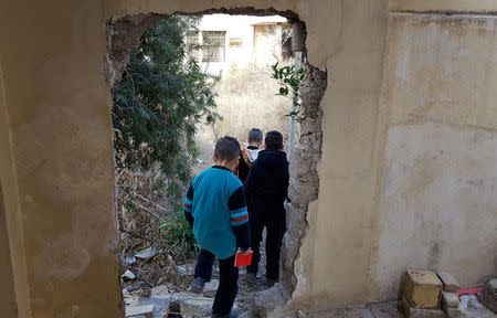 Neighborhood children walk through the man sized holes that Islamic State knocked through the walls in its training facility to allow easy access between the villas in Mosul, Iraq, January 13, 2017. Picture taken January 13, 2017. REUTERS/Stephen Kalin