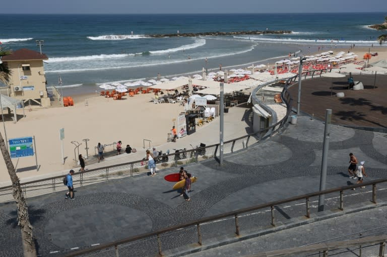 Unos surfistas caminan con sus tablas en una playa en Tel Aviv el 19 de abril de 2024 (Jack Guez)