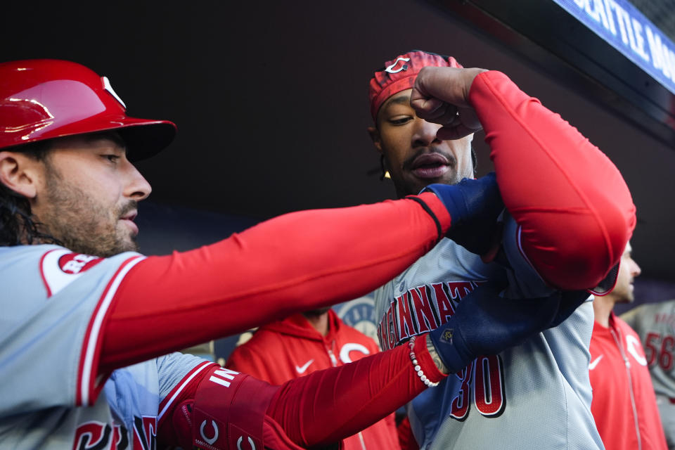 Cincinnati Reds' Jonathan India, left, puts his hands around the bicep of Will Benson, right, in the dugout before the team's baseball game against the Seattle Mariners, Tuesday, April 16, 2024, in Seattle. (AP Photo/Lindsey Wasson)