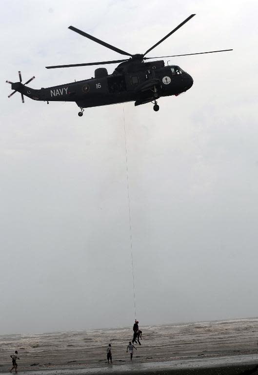 A Pakistan Navy rescuer, hanging from the winch line of a Sea King helicopter, recovers the body of a drowning victim over Clifton beach in Karachi on August 1, 2014