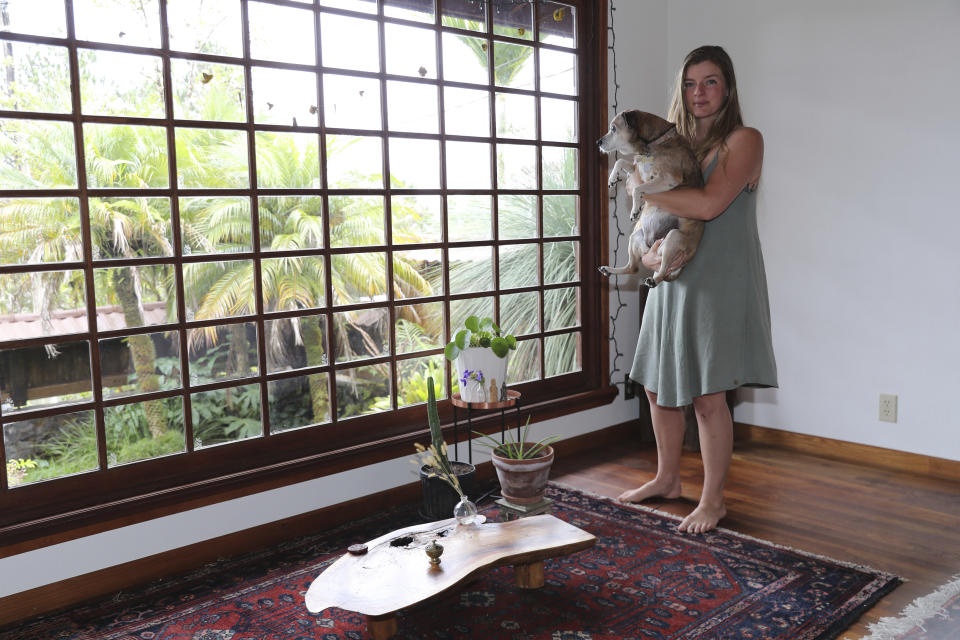 Lindsay Cloyd and her dog, Lily, stand inside their home, Tuesday, Nov. 29, 2022, in Hilo, Hawaii. (AP Photo/Marco Garcia)