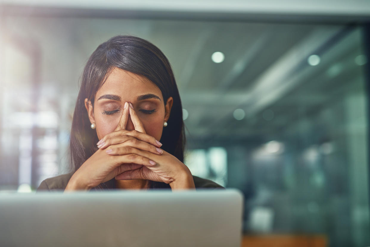 Shot of a young businesswoman looking stressed out while working in an office. Photo: Getty