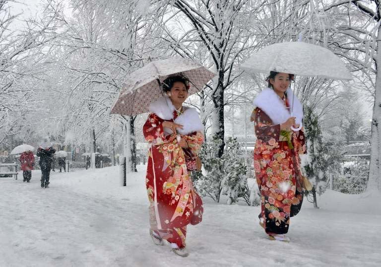 Women dressed in kimonos walk on a snow covered street to a coming-of-age ceremony in Tokyo on January 14, 2013. The winter's first snowfall blanketed the Japanese capital and its environs, paralysing traffic and stranding young people taking part in traditional coming-of-age ceremonies