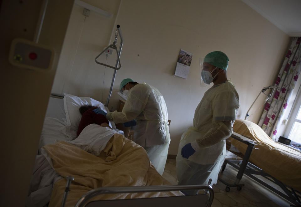 A supervisor, left, and a healthcare worker help a patient suffering from coronavirus to feel more comfortable as they do their rounds in the COVID-19 ward of the CHC nursing home in Landenne, Belgium, Wednesday, Nov. 4, 2020. Belgium, proportionally still the worst-hit nation in Europe when it comes to coronavirus cases, said Wednesday that there were increasing signs of that a turning point in the crisis was drawing close. The Belgian Army has been deployed to help several hard hit areas in the country including nursing homes. (AP Photo/Virginia Mayo)