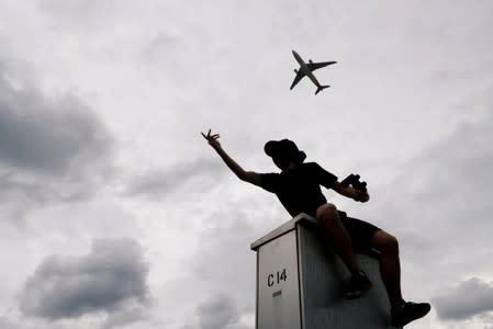 A plane flies over an anti-extradition bill protester as he demonstrates outside the airport in Hong Kong