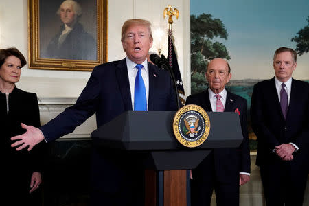 U.S. President Donald Trump, flanked by Lockheed Martin CEO Marillyn Hewson (L), Commerce Secretary Wilbur Ross (2nd R) and U.S. Trade Representative Robert Lighthizer (R), delivers remarks before signing a memorandum on intellectual property tariffs on high-tech goods from China, at the White House in Washington, U.S. March 22, 2018. REUTERS/Jonathan Ernst