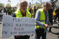 A man holds a sign which reads 'Macron, we don't expect anything from your advertisements' during a yellow vest demonstration in Paris, Saturday, April 20, 2019. French yellow vest protesters are marching anew to remind the government that rebuilding the fire-ravaged Notre Dame Cathedral isn't the only problem the nation needs to solve. (AP Photo/Michel Euler)