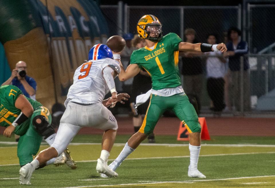 Tracy's Aidan VanOs, right, gets a pass off under pressure from Kimball's Christian Taylor during a varsity football game at Tracy's Wayne Schneider Stadium in Tracy.