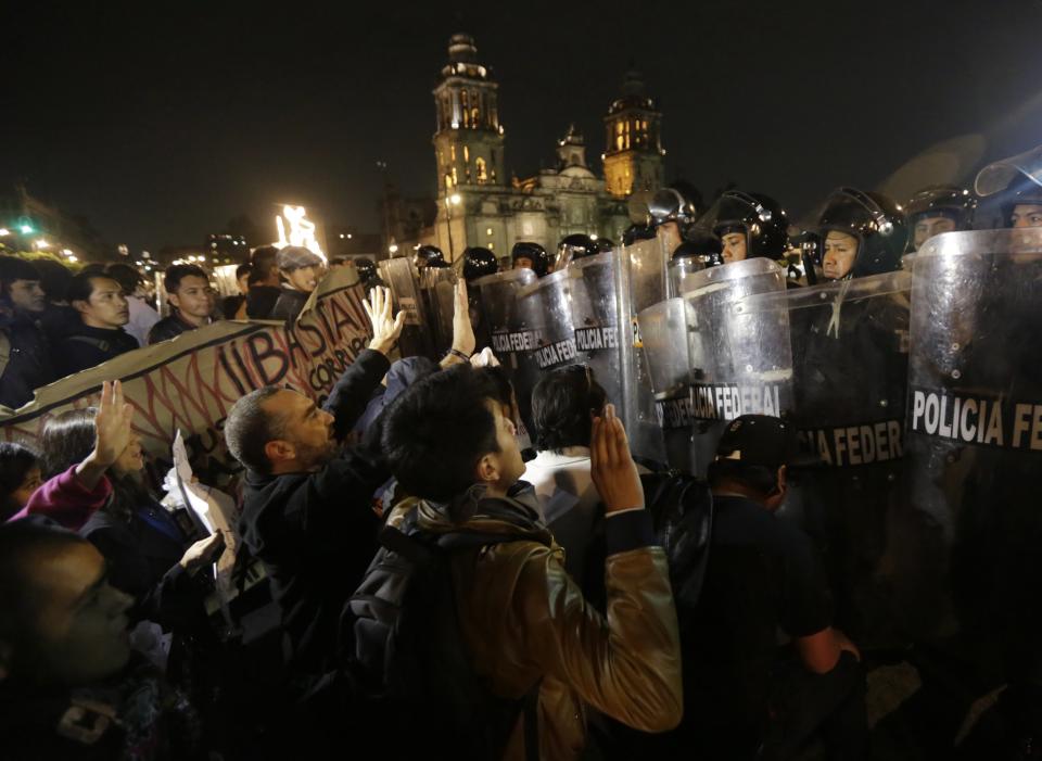 Demonstrators plead with riot police during a protest in support of 43 missing Ayotzinapa students in Mexico City