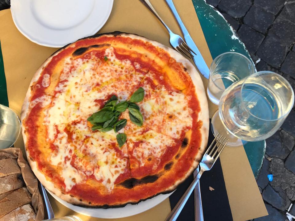 a margherita pizza and glass of white wine rome italy