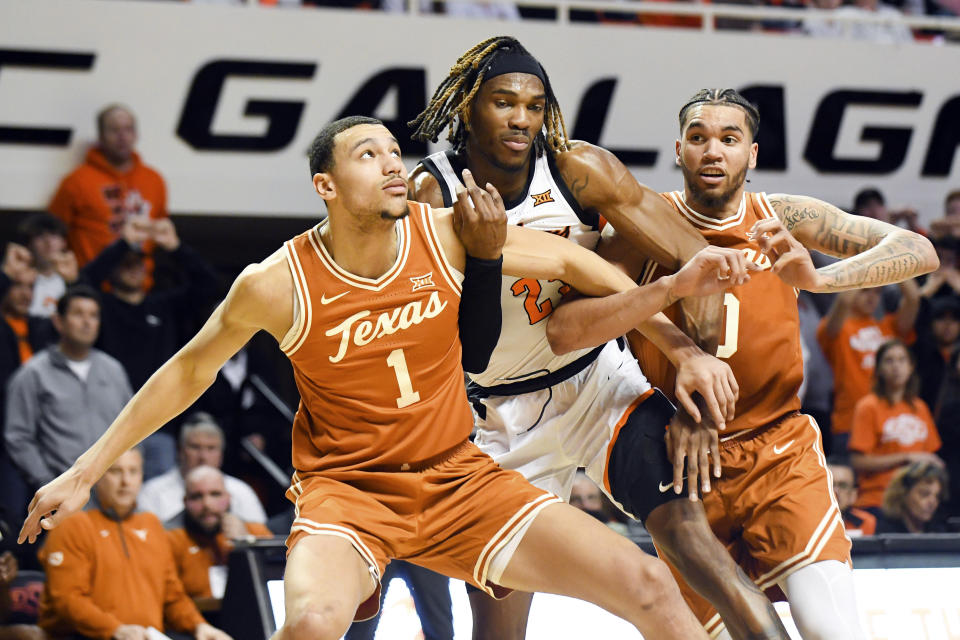 Texas forward Dylan Disu (1) and forward Timmy Allen (0) hold back Oklahoma State forward Tyreek Smith (23) following a free throw during the second half of an NCAA college basketball game Saturday, Jan. 7, 2023, in Stillwater, Okla. Texas defeated Oklahoma State 56-46. (AP Photo/Brody Schmidt)