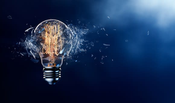 A lit Edison-style bulb shatters in front of a blue background