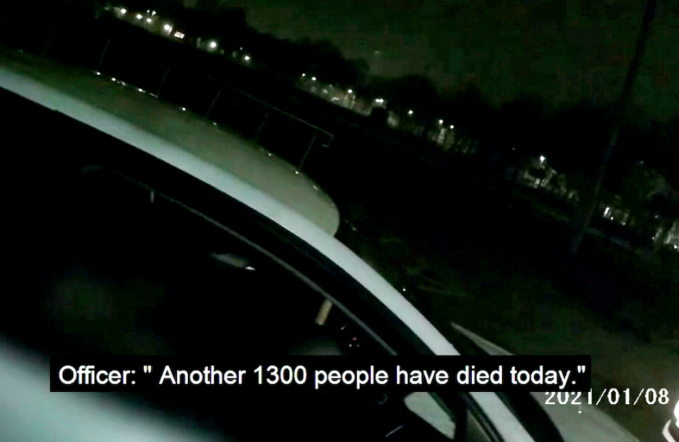 A police officer highlights the COVID deaths to someone breaching lockdown regulations. (SWNS)