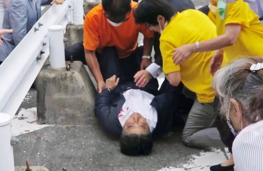 In this image from a video, Japan's former Prime Minister Shinzo Abe, center, is attended on the ground in Nara, western Japan Friday, July 8, 2022. Former Japanese Prime Minister Shinzo Abe, a divisive arch-conservative and one of his nation's most powerful and influential figures, has died after being shot during a campaign speech Friday in western Japan, hospital officials said. (Kyodo News via AP)