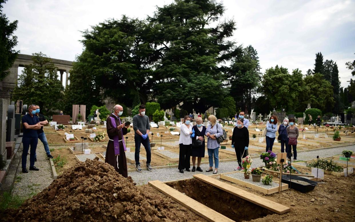 Father Marco Bergamelli (3rdL) prays with relatives of a deceased person during a burial at the Monumental Cemetery of Bergamo, Lombardy - AFP
