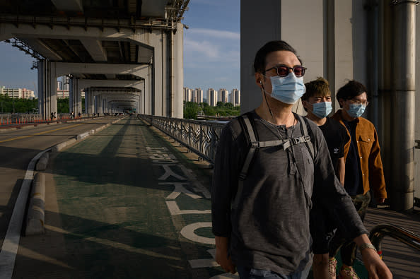 People wearing face masks amid concerns of the COVID-19 novel coronavirus walk along a bridge across the Han river in Seoul. 