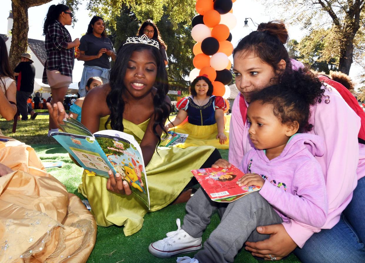 Pacific's student Tamara Maldonado as Bell reads to Halia, 3, and her mom Sandra Goodwin during the Record's Literacy and Book Fair Family Day, held Saturday at University Park on September 15, 2018.