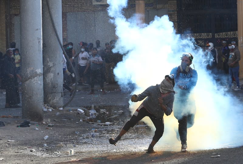 An Iraqi demonstrator throws away a tear gas canister during the ongoing anti-government protests in Baghdad