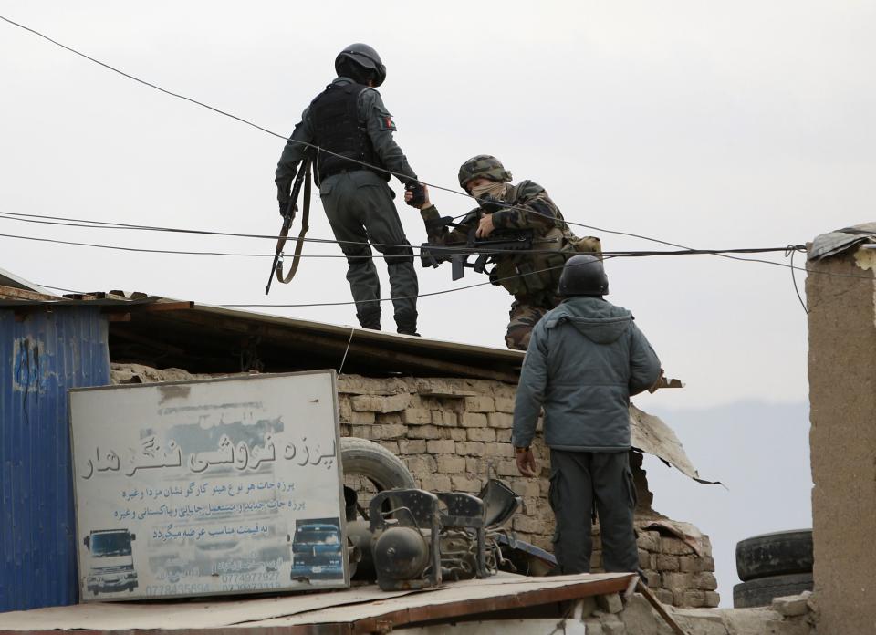 An Afghan policeman helps a serviceman from International Security Assistance Force at the site of a bomb attack in Kabul