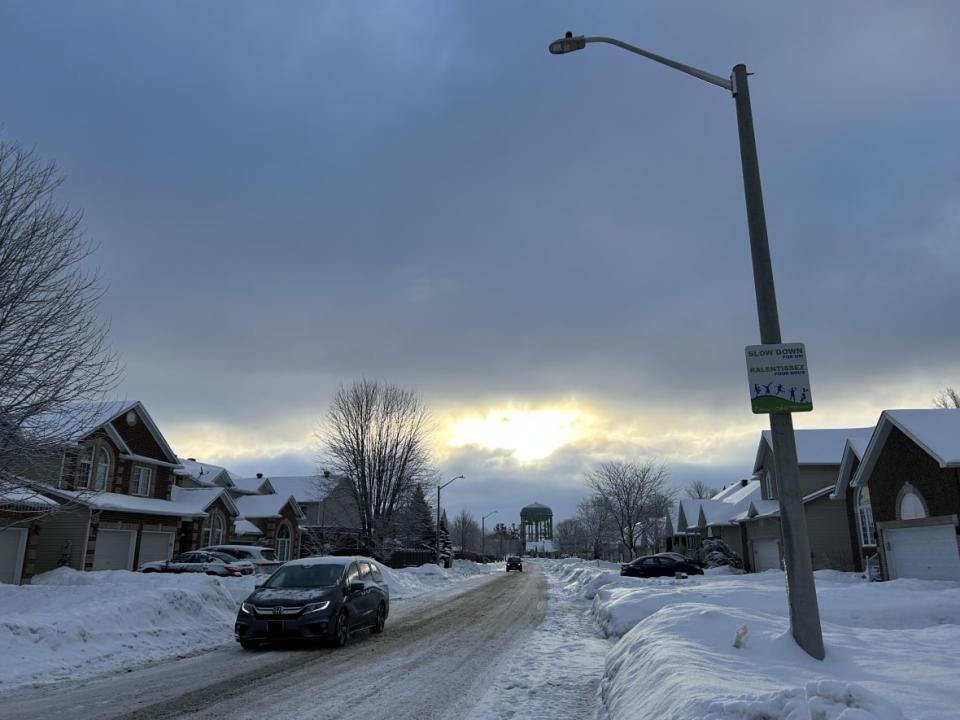 Cars drive down Lloydalex Crescent in Stittsville on Jan. 23. Neighbours along the street say cars regularly speed and ignore stop signs. Like many suburban streets in Ottawa, the area lacks sidewalks.  (Laura Glowacki/CBC - image credit)