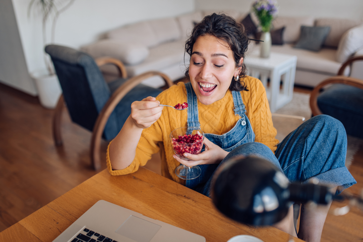 Woman Eating Pomegranate From a Spoon, While in Her Living Room