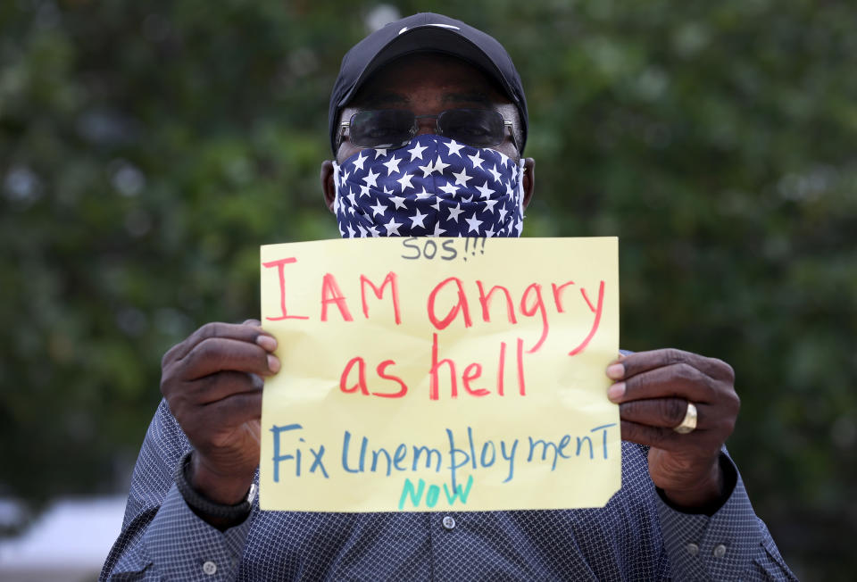 MIAMI BEACH, FLORIDA - MAY 22: Odirus Charles holds a sign that reads, ' I Am angry as hell Fix Unemployment Now,' as he joins others in a protest on May 22, 2020 in Miami Beach, Florida. Unemployed hospitality and service workers who have not received unemployment checks held the protest demanding Florida Governor Ron DeSantis fix the unemployment system and send out their benefits. Since the closure of all non-essential businesses due to the coronavirus pandemic, hundreds of thousands of hospitality workers across Florida find themselves out of work. Florida’s unemployment system has not worked reliably. (Photo by Joe Raedle/Getty Images)