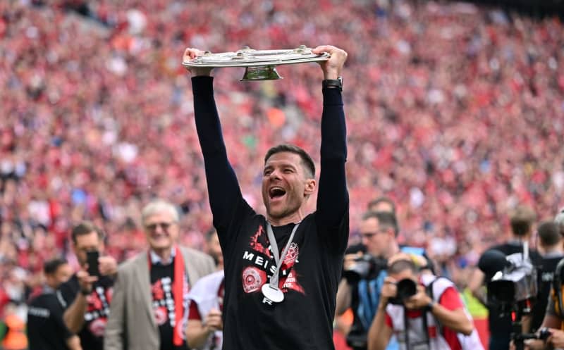 Bayer Leverkusen Coach Xabi Alonso celebrates with the championship trophy following the German Bundesliga soccer match between Bayer Leverkusen and FC Augsburg at BayArena. Marius Becker/dpa